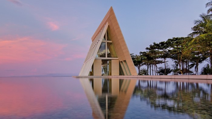 Modern triangular chapel on the water at sunset