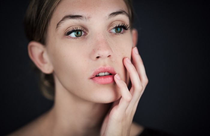 Close-up portrait of a young woman with green eyes and freckles