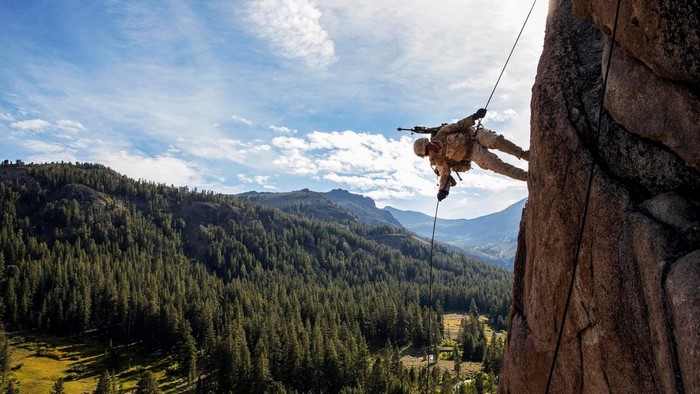 Soldier rappelling down a rocky mountain face