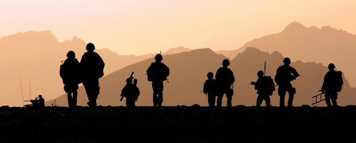 Silhouettes of soldiers against a mountain sunset