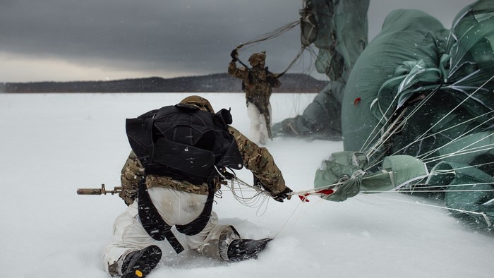Soldiers parachuting in a snowy landscape