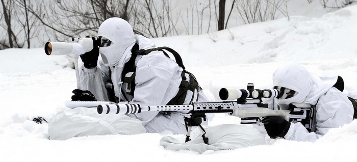 Two soldiers in camouflage in the snow with rifles