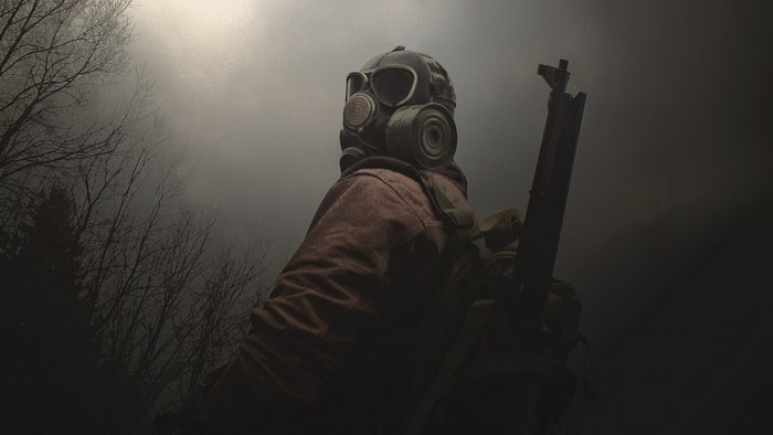 Soldier with gas mask and rifle in foggy forest