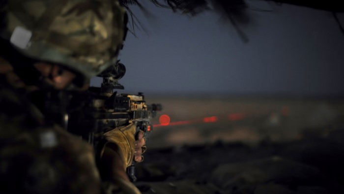 Soldier aiming a rifle with a laser sight at night