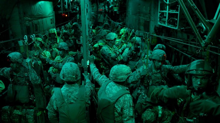 Soldiers in military gear inside a transport aircraft at night