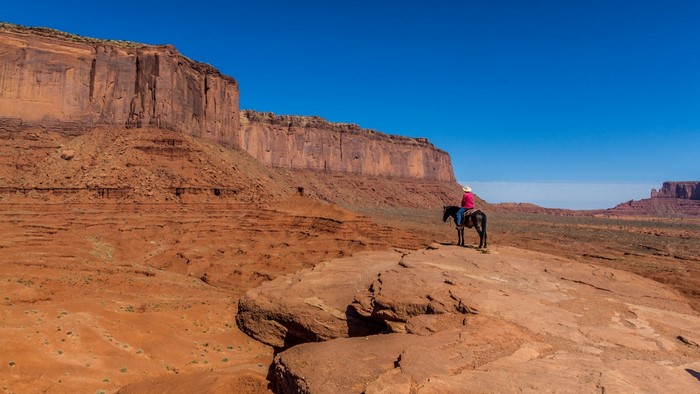 Cowboy on horseback in Monument Valley desert landscape