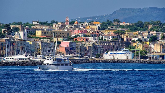 Boats in a harbor with colorful buildings and a hill