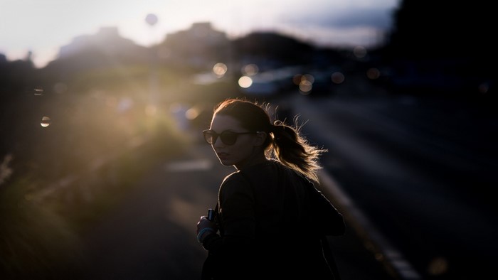Woman with sunglasses in backlighting at sunset