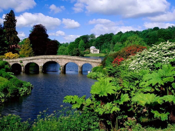 Stone bridge over a lake with a temple in the background
