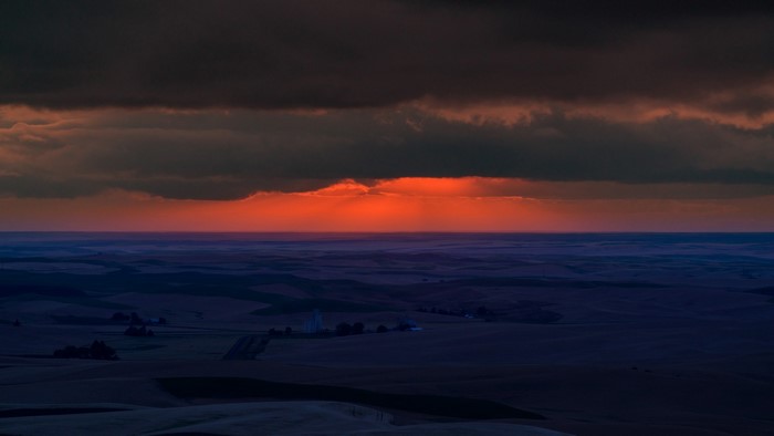 Sunset over rolling hills with dark clouds