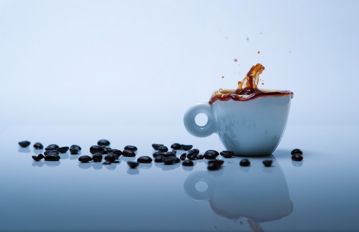 Espresso cup with coffee splash and beans