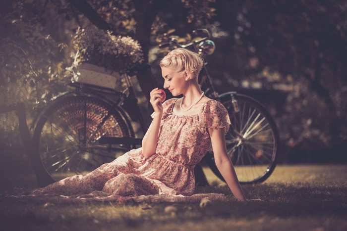 Woman in floral dress with apple and bicycle