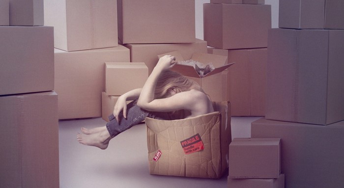 Woman and cat in a box surrounded by moving boxes