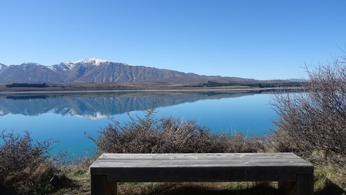 Bench overlooking Lake Tekapo with snowy mountains