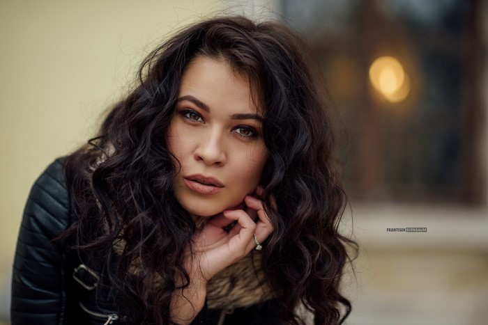 Woman with long dark wavy hair wearing a leather jacket