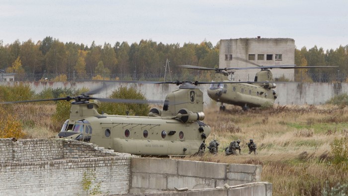 Two United States Army CH-47 Chinook helicopters land near soldiers