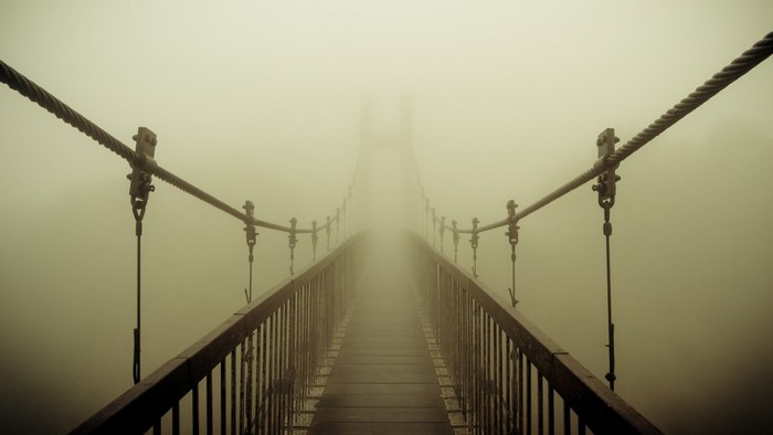 Suspension bridge disappearing into thick fog