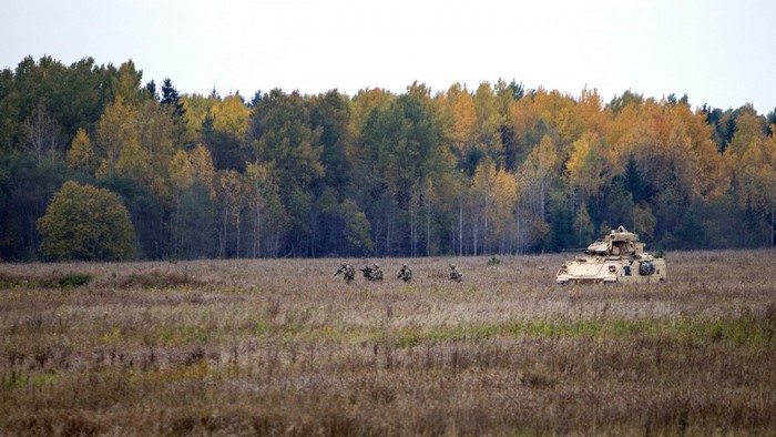 Soldiers and Bradley IFV in a field with autumn trees