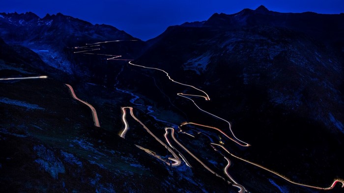 Mountain road with car light trails at night