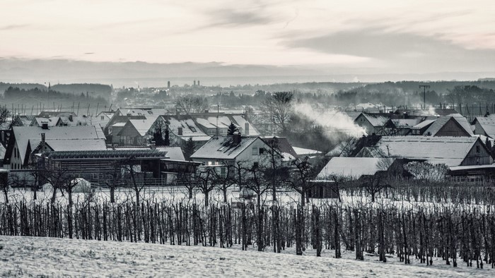 Snowy village with smoke rising from chimneys in winter