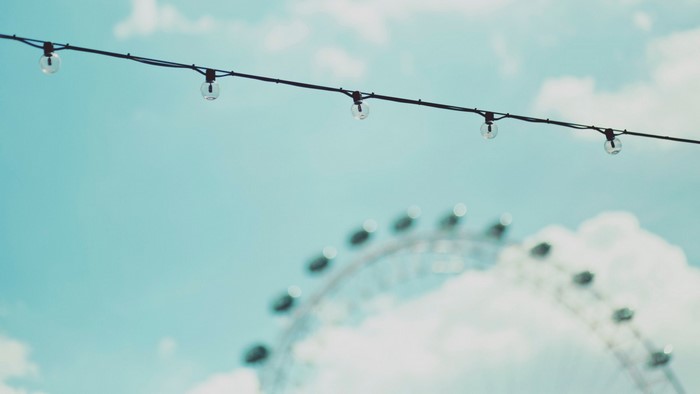 String of lights against the sky with a blurred Ferris wheel