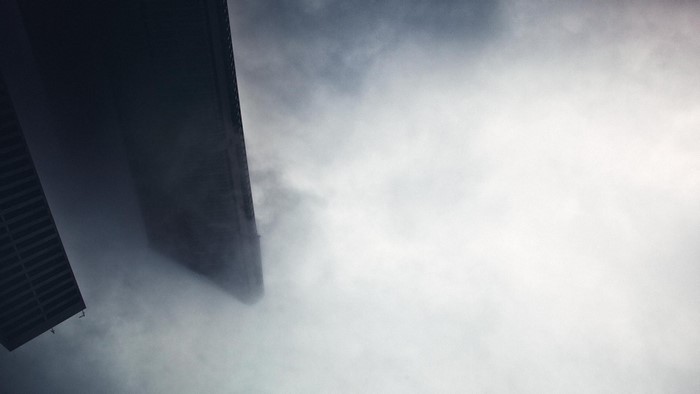 Buildings shrouded in mist against a cloudy sky