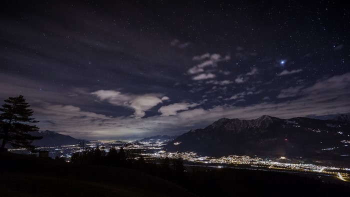 Night sky over mountains and illuminated town