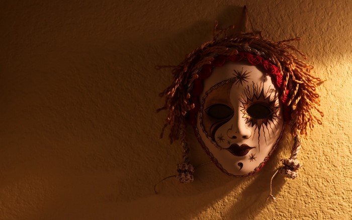 Venetian mask with red and gold accents hanging on a wall