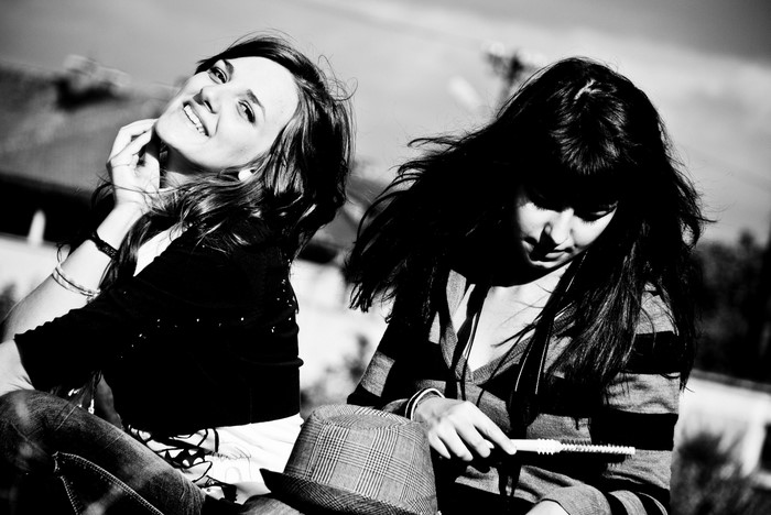 Two young women posing outdoors in black and white
