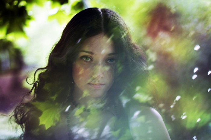 Portrait of a woman with dark wavy hair in a forest