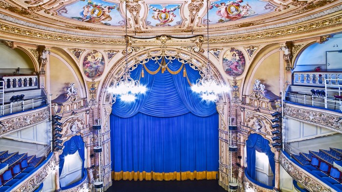 Interior of a grand opera house with a blue stage curtain