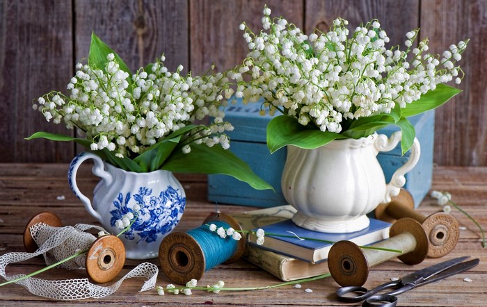 Lily of the valley flowers in vases with spools and scissors