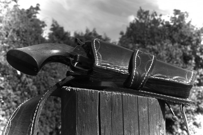 Revolver in a leather holster on a wooden post