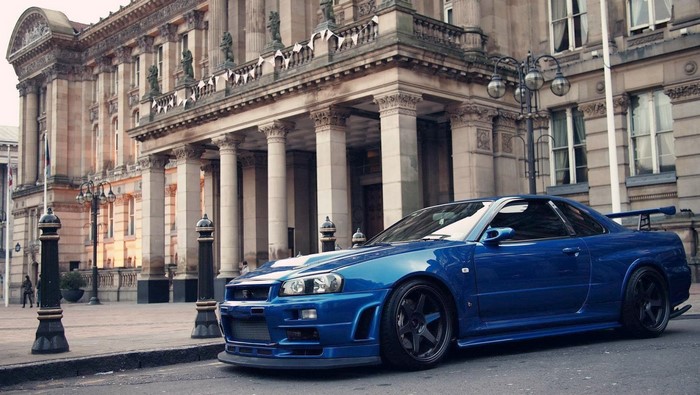 Blue Nissan Skyline GT-R R34 in front of a building