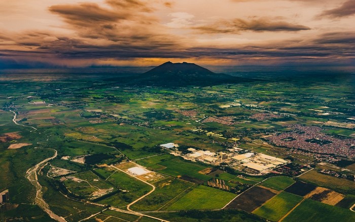 Aerial view of a valley with a volcano under dramatic clouds