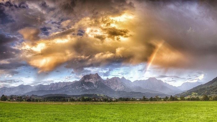 Rainbow over mountains and green field