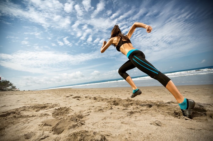 Woman Running on the Beach Under Blue Sky