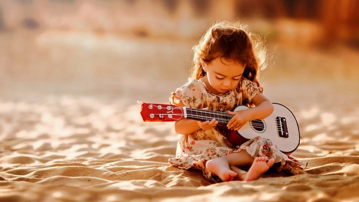 Girl playing a ukulele on the beach