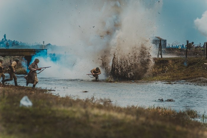 Soldiers crossing a river during a battle with an explosion