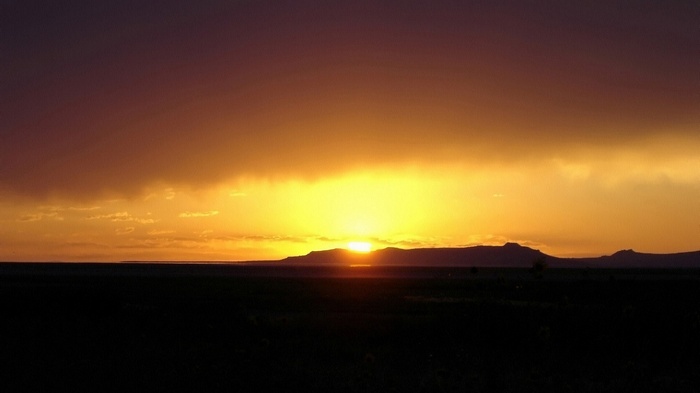 Sunset over a dark landscape with mountains