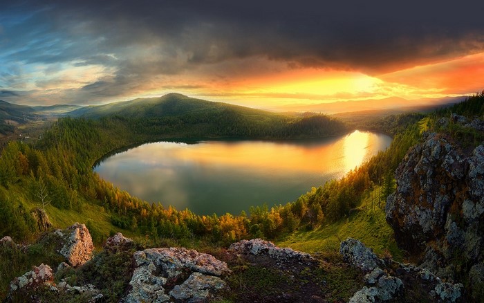 Lake reflection at sunset with forest and mountains