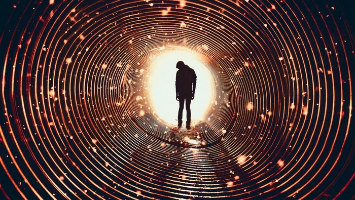 Silhouette of a man in a glowing spiral tunnel