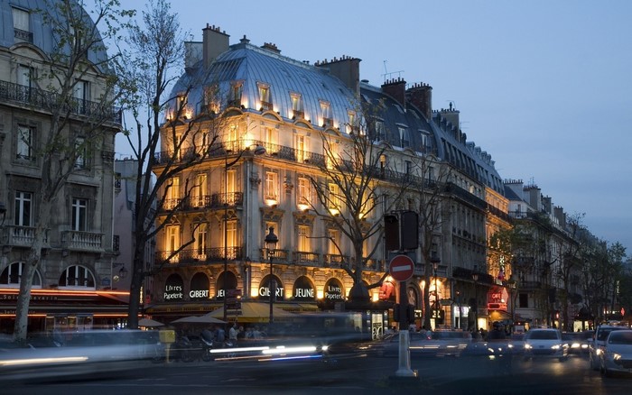 Parisian street at dusk with illuminated buildings and blurred cars