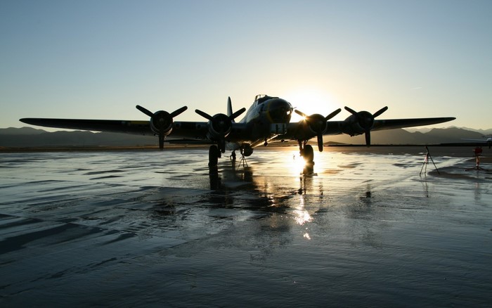Boeing B-17 Flying Fortress bomber on wet tarmac at sunset