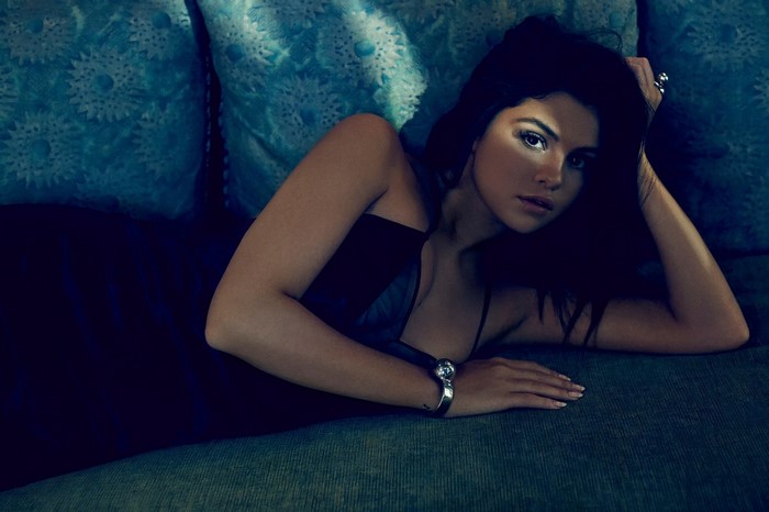 Selena Gomez lying on a blue couch