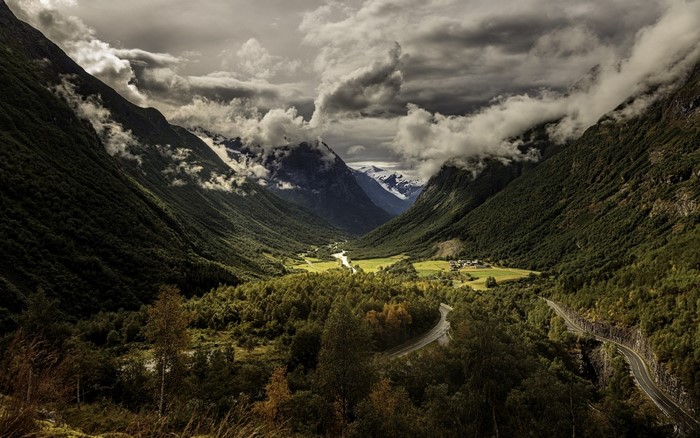 Valley with mountains, clouds, and a winding road
