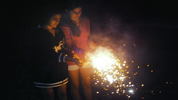 Two girls holding sparklers at night