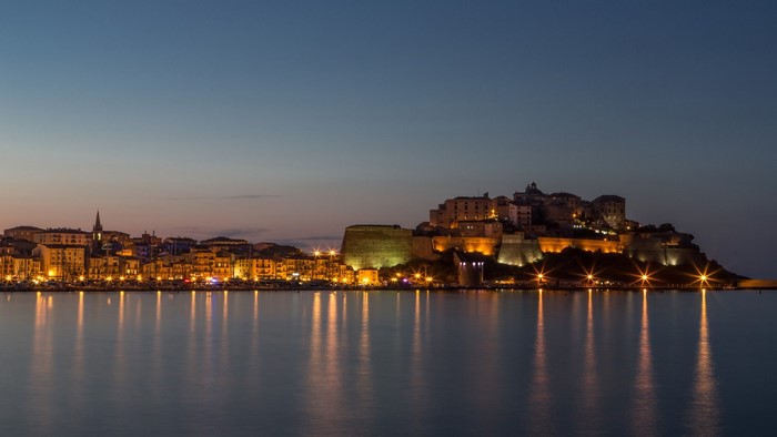 Cityscape with fortress on a hill overlooking the sea at dusk