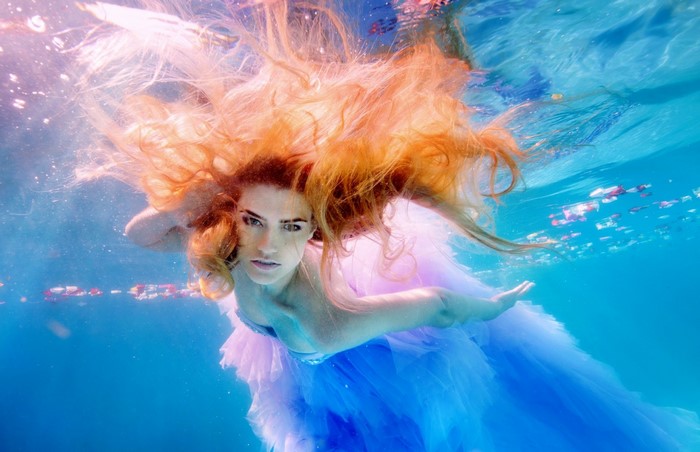 Redhead woman in blue and pink dress underwater
