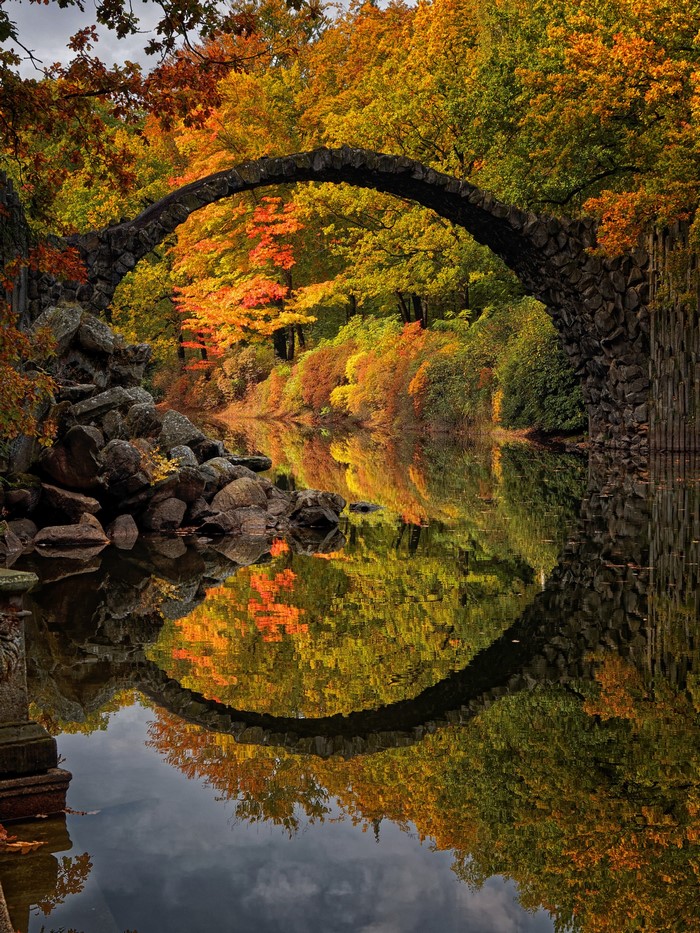 Rakotzbrücke bridge over river in autumn forest, Germany